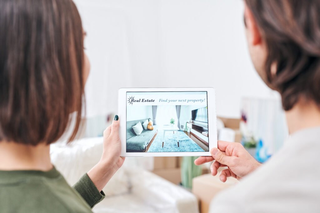 Young couple holding tablet with advertisement of real estate on sale and discussing it while looking for new house or flat