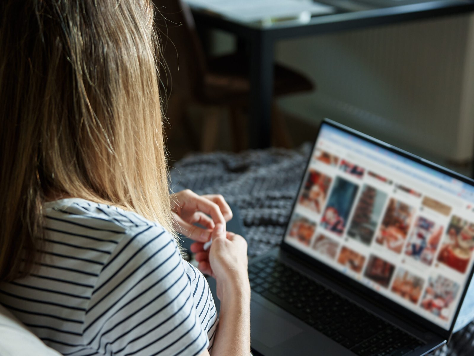 Woman sitting on sofa in living room and using laptop. Female freelancer working at home office. Remote work and work from home concept.