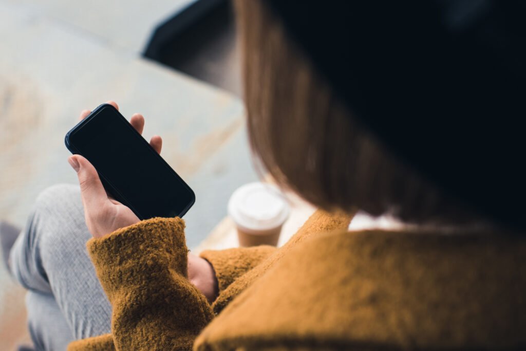 partial view of stylish woman holding smartphone with blank screen